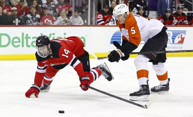 New Jersey Devils right wing Nathan Bastian (14) plays the puck against Philadelphia Flyers defenseman Egor Zamula (5) during the second period of an NHL hockey game, Saturday, Jan. 18, 2025, in Newark, N.J. (AP Photo/Noah K. Murray)