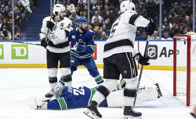 Los Angeles Kings' Alex Turcotte (15) scores against Vancouver Canucks goaltender Thatcher Demko, bottom left, as Canucks' Filip Hronek (17) and Kings' Phillip Danault, top left, watch during the first period of an NHL hockey game in Vancouver, British Columbia, Thursday, Jan. 16, 2025. (Ethan Cairns/The Canadian Press via AP)