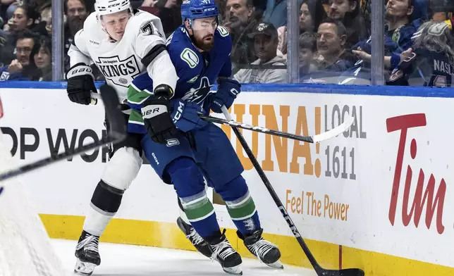 Los Angeles Kings' Samuel Helenius (79) and Vancouver Canucks' Filip Hronek (17) vie for the puck during the first period of an NHL hockey game in Vancouver, British Columbia, Thursday, Jan. 16, 2025. (Ethan Cairns/The Canadian Press via AP)
