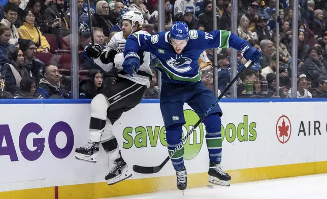 Vancouver Canucks' Vincent Desharnais (73) hits Los Angeles Kings' Warren Foegele, left, during the second period of an NHL hockey game in Vancouver, British Columbia, Thursday, Jan. 16, 2025. (Ethan Cairns/The Canadian Press via AP)