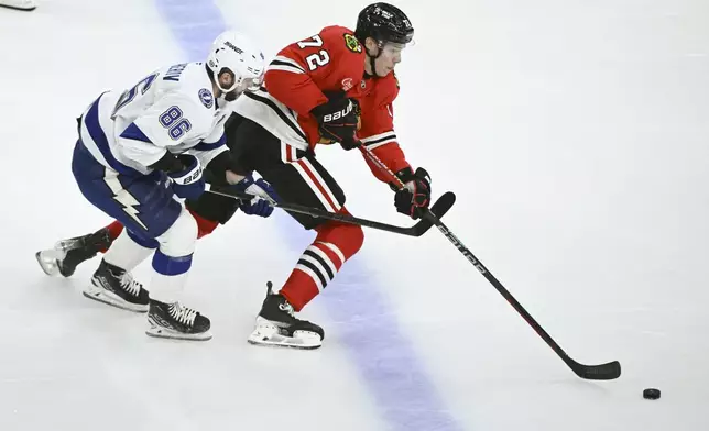 Chicago Blackhawks defenseman Alex Vlasic (72) moves the puck past Tampa Bay Lightning right wing Nikita Kucherov (86) during the second period of an NHL hockey game, Friday, Jan. 24, 2025, in Chicago. (AP Photo/Matt Marton)