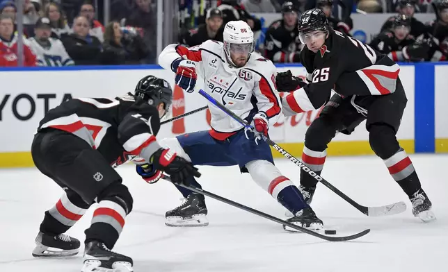 Washington Capitals left wing Pierre-Luc Dubois, center, tries to split the defense of Buffalo Sabres defensemen Owen Power, right, and Henri Jokiharju during the first period of an NHL hockey game in Buffalo, N.Y., Monday, Jan. 6, 2025. (AP Photo/Adrian Kraus)