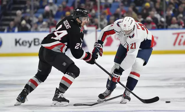 Buffalo Sabres center Dylan Cozens, left, reaches for the puck as Washington Capitals center Aliaksei Protas loses his stick during the first period of an NHL hockey game in Buffalo, N.Y., Monday, Jan. 6, 2025. (AP Photo/Adrian Kraus)