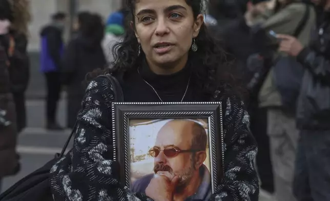 Wafaa Mustafa, center, holds a picture of her missing father during a demonstration in Damascus, Syria, on Dec. 2024. (AP Photo/Ghaith Alsayed)