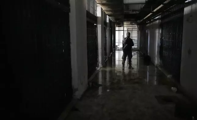 A member of the security forces for the new interim Syrian government stands next to prison cells at the Palestine Branch, a detention facility operated by the General Intelligence Agency during Bashar Assad's regime, in Damascus, Syria, on Dec. 14, 2024. (AP Photo/Hussein Malla)