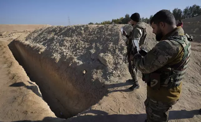 Fighters who helped oust former Syrian ruler Bashar Assad examine a site identified as a mass grave for prisoners killed under his rule in Najha, south of Damascus, Syria, on Dec. 17, 2024. (AP Photo/Hussein Malla)