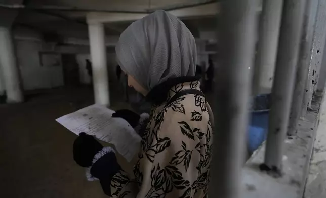 A woman inspects documents in search of the name of a missing relative at Syria's infamous Saydnaya military prison, located just north of Damascus on Dec. 9, 2024. (AP Photo/Hussein Malla)