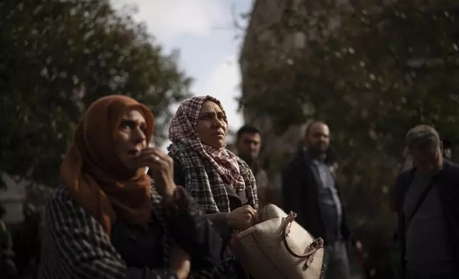 FILE - Hanaa al-Khodr, center, and her mother, Khawla al-Khodr, left, look at photos of people reported missing after being taken by members of ousted Syrian President Bashar Assad's army in Damascus, Syria, on Dec. 22, 2024. (AP Photo/Leo Correa, File)