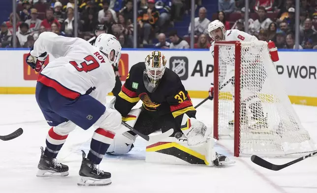 Vancouver Canucks goalie Kevin Lankinen (32) stops Washington Capitals' Matt Roy (3) during the first period of an NHL hockey game in Vancouver, Saturday, Jan. 25, 2025. (Darryl Dyck/The Canadian Press via AP)