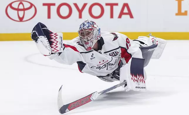 Washington Capitals goalie Charlie Lindgren dives to make a glove save after being caught out of position while skating to the bench for the extra attacker during the third period of an NHL hockey game in Vancouver, British Columbia, on Saturday, Jan. 25, 2025. (Darryl Dyck/The Canadian Press via AP)