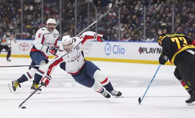 Washington Capitals' Dylan Strome (17) reaches for the puck against Vancouver Canucks' Vincent Desharnais (73) as Washington's Alex Ovechkin (8) watches during the first period of an NHL hockey game in Vancouver, Saturday, Jan. 25, 2025. (Darryl Dyck/The Canadian Press via AP)