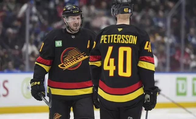 Vancouver Canucks' J.T. Miller talks to Elias Pettersson (40) before the second period of an NHL hockey game against Washington Capitals in Vancouver, British Columbia, on Saturday, Jan. 25, 2025. (Darryl Dyck/The Canadian Press via AP)