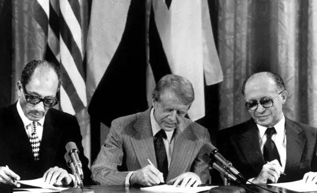 FILE - From left, Egyptian President Anwar Sadat, U.S. President Jimmy Carter, and Israeli Prime Minister Menachem Begin sign one of two agreements forged at the Camp David summit during a joint announcement at the White House on Sept. 17, 1978. (AP Photo, File)