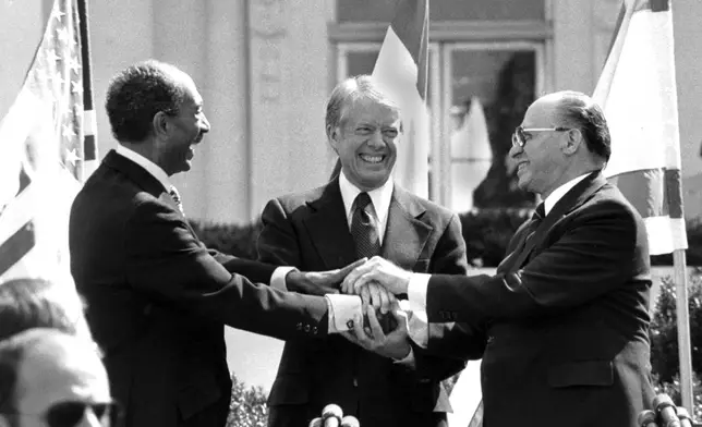 FILE - Egyptian President Anwar Sadat, left, U.S. President Jimmy Carter, center, and Israeli Prime Minister Menachem Begin clasp hands on the north lawn of the White House after signing the peace treaty between Egypt and Israel on March 26, 1979, in Washington. (AP Photo/ Bob Daugherty, File)