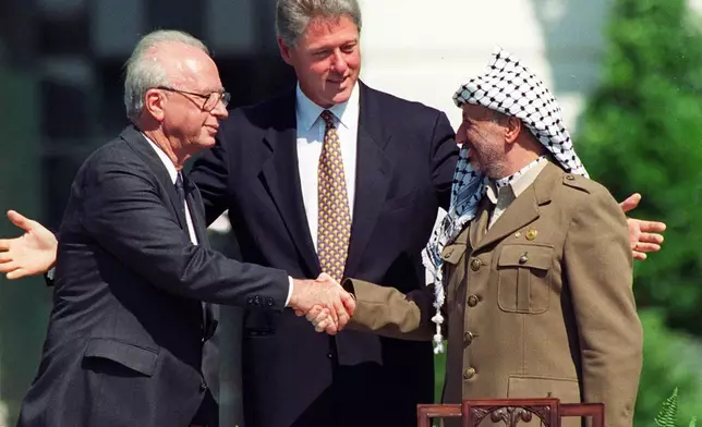 FILE - U.S. President Bill Clinton watches as Israeli Prime Minister Yitzhak Rabin, left, and Palestinian leader Yasser Arafat shake hands, marking the signing of the peace accord between Israel and the Palestinians, in Washington on Sept. 13, 1993. (AP Photo/Ron Edmonds, File)