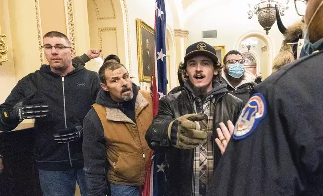 FILE - Violent protesters loyal to President Donald Trump, including Kevin Seefried, center, holding a Confederate battle flag, are confronted by U.S. Capitol Police officers outside the Senate Chamber inside the Capitol, Jan. 6, 2021 in Washington. (AP Photo/Manuel Balce Ceneta, File)