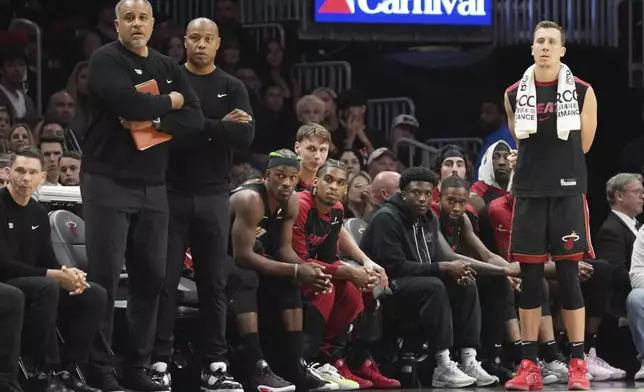 Miami Heat forward Jimmy Butler, third from left, and forward Duncan Robinson, right, watch from the bench during the second half of an NBA basketball game against the Indiana Pacers Thursday, Jan. 2, 2025, in Miami. (AP Photo/Lynne Sladky)