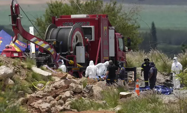Forensic service workers carry body remains in blue body bags during a rescue operation to rescue miners from below ground in an abandoned gold mine in Stilfontein, South Africa, Wednesday, Jan. 15, 2025. (AP Photo/Themba Hadebe)