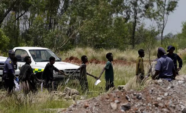 Illegal miners escorted by police officers after being rescued from an abandoned gold mine in Stilfontein, South Africa, Tuesday, Jan. 14, 2025. (AP Photo/Themba Hadebe)
