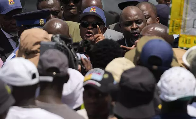 South Africa's Police minister Senzo Mchunu, center, attempts talking to family members and activists after visiting an abandoned gold mine, where miners are rescued from below ground, in Stilfontein, South Africa, Tuesday, Jan. 14, 2025. (AP Photo/Themba Hadebe)