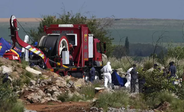 Forensic service workers carry remains in blue body bags during a rescue operation to rescue miners from below ground in an abandoned gold mine in Stilfontein, South Africa, Tuesday, Jan. 14, 2025. (AP Photo/Themba Hadebe)