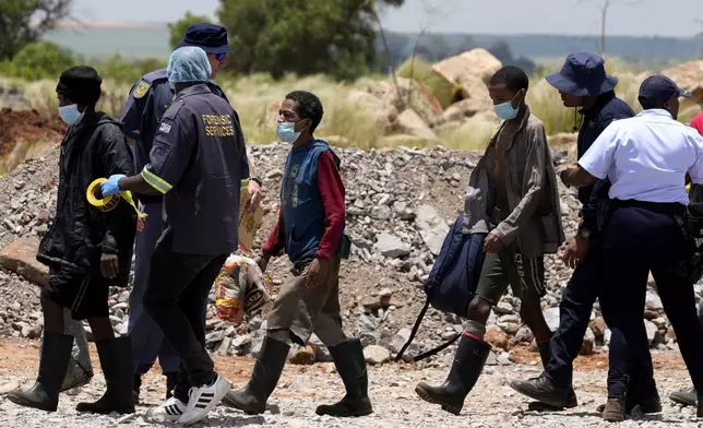 Illegal miners are escorted by police officers after being rescued from an abandoned gold mine for months, in Stilfontein, South Africa, Tuesday, Jan. 14, 2025. (AP Photo/Themba Hadebe)