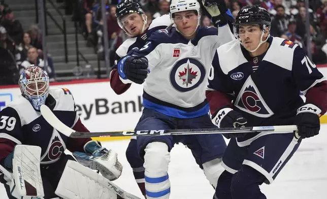 Winnipeg Jets center Rasmus Kupari, center front, pursues the puck with Colorado Avalanche defenseman Sam Malinski, right, as Avalanche goaltender Mackenzie Blackwood, left, looks on in the second period of an NHL hockey game Tuesday, Dec. 31, 2024, in Denver. (AP Photo/David Zalubowski)