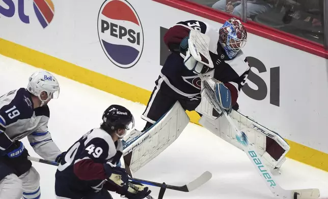 Colorado Avalanche goaltender Mackenzie Blackwood, right, clears the puck as defenseman Samuel Girard, center, blocks Winnipeg Jets center David Gustafsson in the third period of an NHL hockey game Tuesday, Dec. 31, 2024, in Denver. (AP Photo/David Zalubowski)