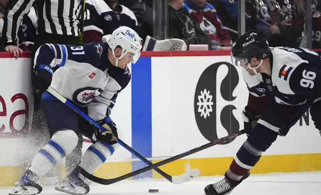 Winnipeg Jets center Cole Perfetti, left, fights for control of the puck as Colorado Avalanche right wing Mikko Rantanen, right, defends in the second period of an NHL hockey game Tuesday, Dec. 31, 2024, in Denver. (AP Photo/David Zalubowski)