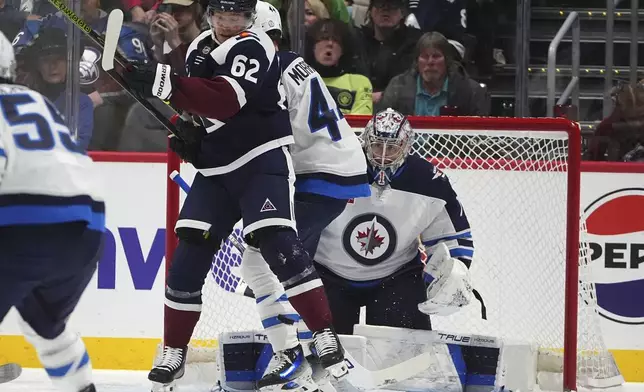 Colorado Avalanche left wing Artturi Lehkonen (62) battles for position in front of the net with Winnipeg Jets defenseman Ville Heinola, center, as Jets goaltender Eric Comrie, right, looks for the puck in the second period of an NHL hockey game Tuesday, Dec. 31, 2024, in Denver. (AP Photo/David Zalubowski)