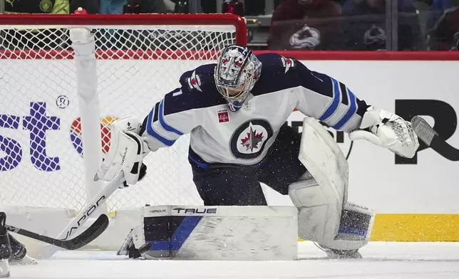 Winnipeg Jets goaltender Eric Comrie stops a shot in the second period of an NHL hockey game against the Colorado Avalanche, Tuesday, Dec. 31, 2024, in Denver. (AP Photo/David Zalubowski)