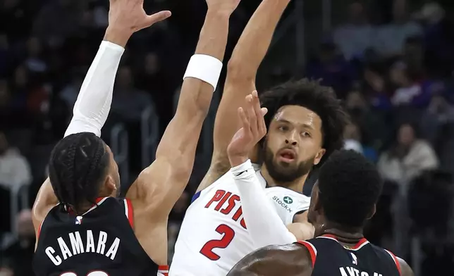 Detroit Pistons guard Cade Cunningham (2) passes the ball against Portland Trail Blazers forward Toumani Camara (33) and center Deandre Ayton (2) during the first half of an NBA basketball game, Monday, Jan. 6, 2025, in Detroit. (AP Photo/Duane Burleson)