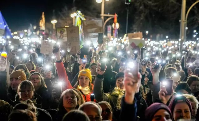 People hold up their cell phones as they protest the far-right Alternative for Germany, or AfD party, and right-wing extremism in front of the Brandenburg Gate in Berlin, Germany, Saturday, Jan. 25, 2025. (AP Photo/Ebrahim Noroozi)