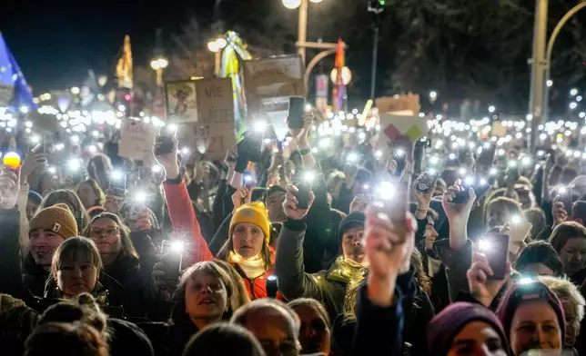 People hold up their cell phones as they protest the far-right Alternative for Germany, or AfD party, and right-wing extremism in front of the Brandenburg Gate in Berlin, Germany, Saturday, Jan. 25, 2025. (AP Photo/Ebrahim Noroozi)