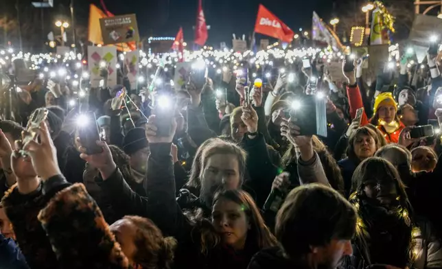 People hold up their cell phones as they protest the far-right Alternative for Germany, or AfD party, and right-wing extremism in front of the Brandenburg Gate in Berlin, Germany, Saturday, Jan. 25, 2025. (AP Photo/Ebrahim Noroozi)