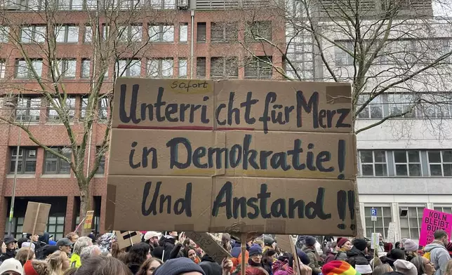 People gather to protest against the Far Right, in Cologne, Germany, Saturday Jan. 25, 2025. Banner reads: "Immediate lessons for Merz in democracy and decency". (Christoph Driessen/dpa via AP)