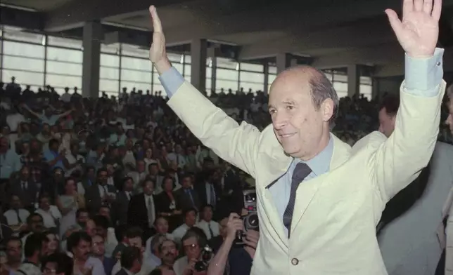 FILE - Then Greek Premier Costas Simitis, waves to ruling Socialist party's congress delegates shortly before the start of his speech in Athens on Thursday June 27, 1996. Costas Simitis, a Prime Minister of Greece from 1996 to 2004 and the architect of the country's joining the common European currency, the euro, has died at 88, state TV ERT reports. (AP photo/ Aris Saris, File)