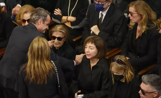 Greece's Prime Minister Kyriakos Mitsotakis pays his respects to the wife Daphne Simitis, left, daughters Fiona, center, and Marilena of the late Costas Simitis former Prime Minister, during the state funeral in Athens' central cathedral, Thursday, Jan. 9, 2025. (AP Photo/Petros Giannakouris)