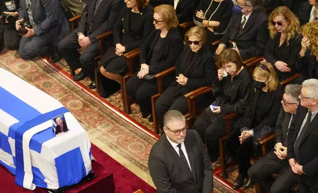 The family of the late Costas Simitis former Prime Minister, his wife Daphne Simitis, fifth left, daughters Fiona, fourth left, and Marilena third left, sit next to the Greek flag-draped casket during the state funeral in Athens' central cathedral, Thursday, Jan. 9, 2025. (AP Photo/Petros Giannakouris)