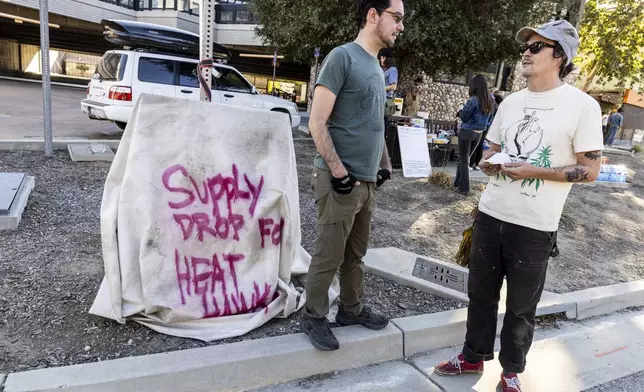 Bobby Ognyanov, left, chats with Cody "Toad" Webb outside Topanga Library as a volunteer group known as the Heat Hawks organizes mutual aid to the community during the Palisades Fire in Topanga, Calif., Thursday, Jan. 9, 2025. (Stephen Lam/San Francisco Chronicle via AP)