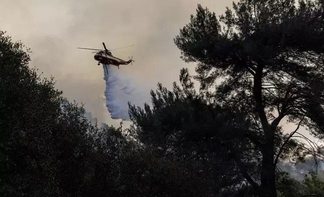 A firefighting helicopter releases water on a hot spot while battling the Palisades Fire in Topanga, Calif., Thursday, Jan. 9, 2025.(Stephen Lam/San Francisco Chronicle via AP)