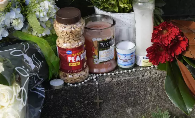 A jar of peanuts is among the items left in tribute to former President Jimmy Carter at the entrance to the Jimmy Carter Presidential Center Tuesday, Dec. 31, 2024, in Atlanta. Carter died Sunday at he age of 100. (AP Photo/John Bazemore )