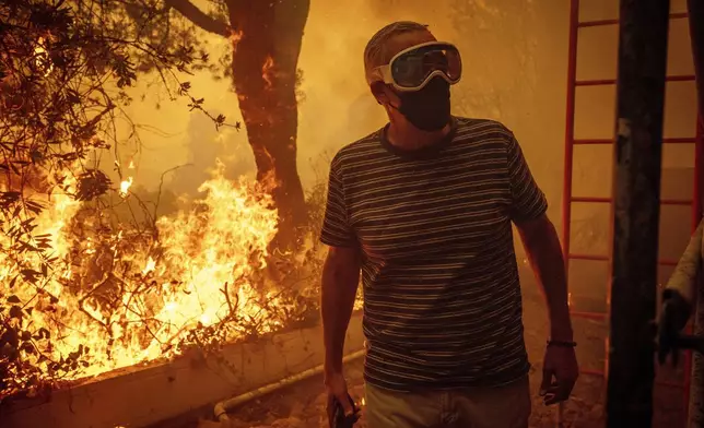 Will Adams watches as flames from the Palisades Fire close in on his property in the Pacific Palisades neighborhood of Los Angeles, Tuesday, Jan. 7, 2025. (AP Photo/Ethan Swope)