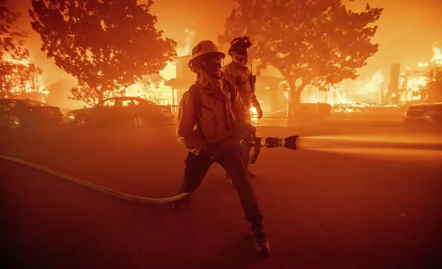 Firefighters battle the Palisades Fire as it burns multiple structures in the Pacific Palisades neighborhood of Los Angeles, Tuesday, Jan. 7, 2025. (AP Photo/Ethan Swope)