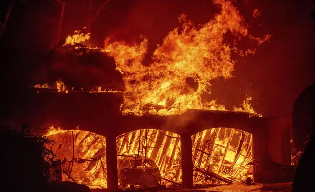 The Eaton Fire burns a residence Wednesday, Jan. 8, 2025 in Altadena, Calif. (AP Photo/Ethan Swope)