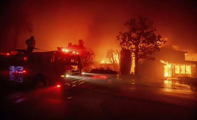 Fire crews battle the Palisades Fire as it burns multiple structures in the Pacific Palisades neighborhood of Los Angeles, Tuesday, Jan. 7, 2025. (AP Photo/Ethan Swope)