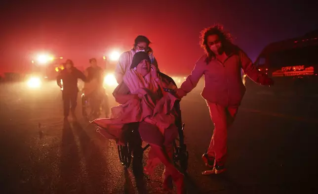 Residents of a senior center are evacuated as the Eaton Fire approaches Tuesday, Jan. 7, 2025 in Altadena, Calif. (AP Photo/Ethan Swope)