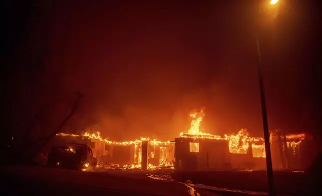 The Eaton Fire burns a structure Wednesday, Jan. 8, 2025 in Altadena, Calif. (AP Photo/Ethan Swope)