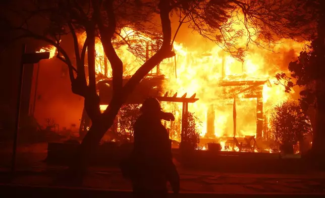 A firefighter battles the Palisades Fire in the Pacific Palisades neighborhood of Los Angeles, Tuesday, Jan. 7, 2025. (AP Photo/Etienne Laurent)