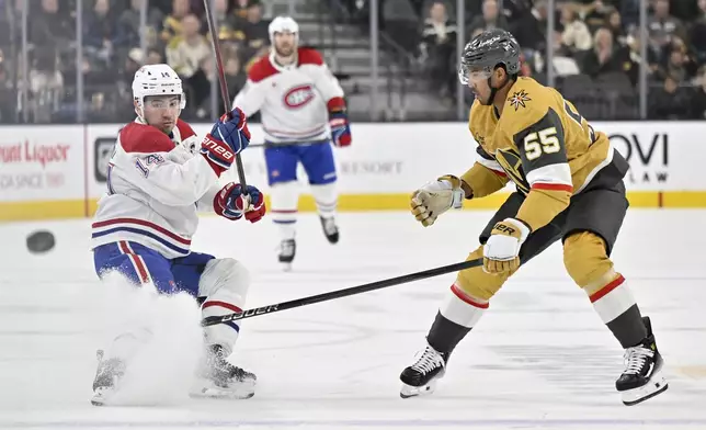 Montreal Canadiens center Nick Suzuki (14) hits the puck down ice against Vegas Golden Knights right wing Keegan Kolesar (55) during the first period of an NHL hockey game Tuesday, Dec. 31, 2024, in Las Vegas. (AP Photo/David Becker)